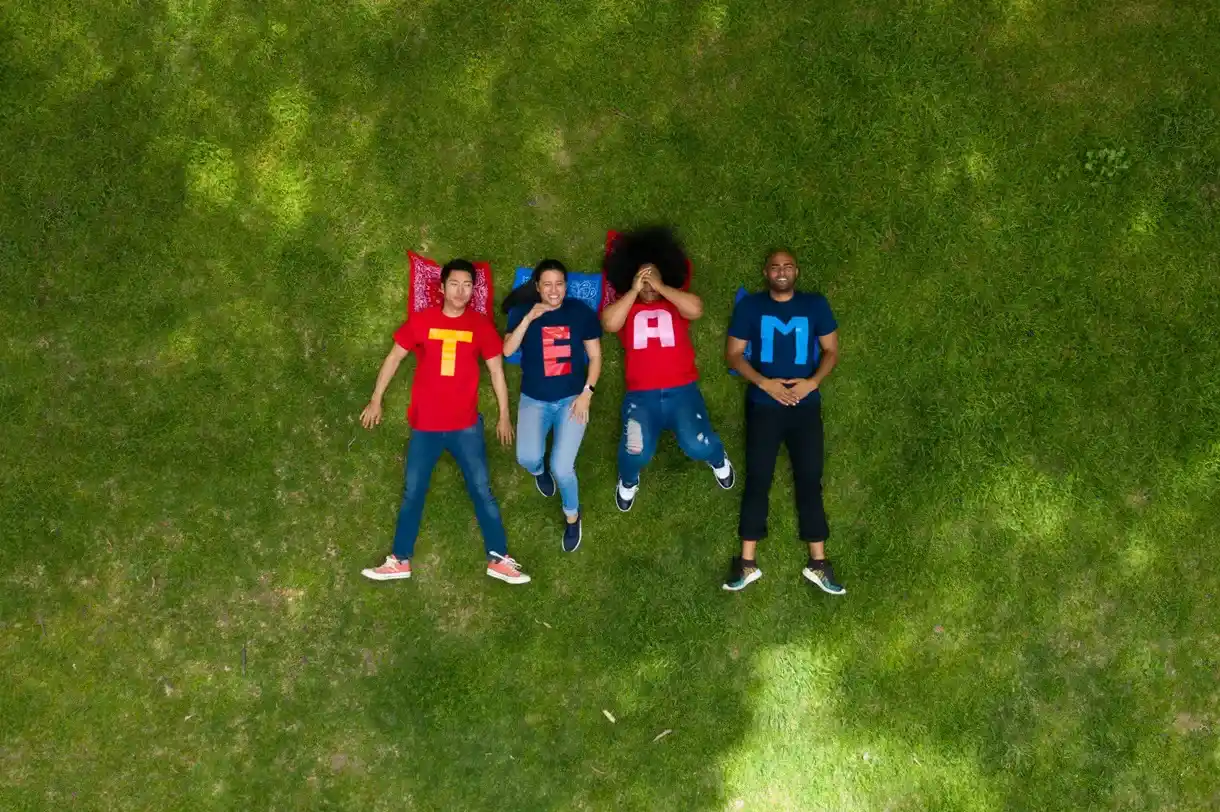 Team liegt gemeinsam bei ihrem Teamevent auf einer Wiese.